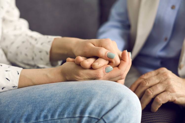 Loving young woman holding her senior mother's hand comforting and supporting her
